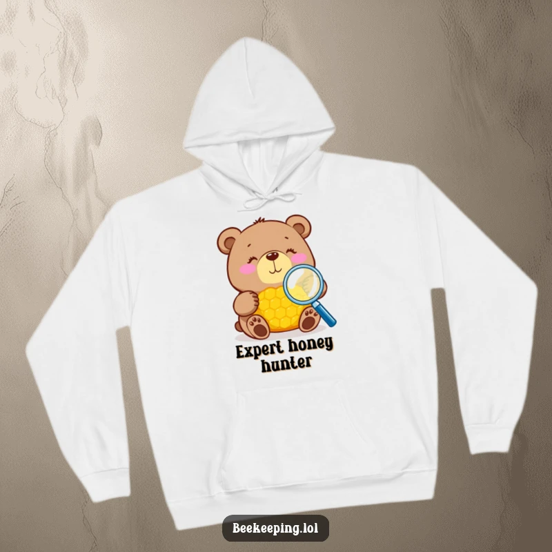 Funny bear with magnifying glass inspecting honeycomb on a cozy hoodie, warm and humorous, perfect gift.