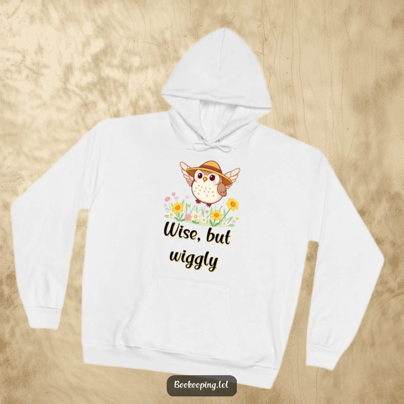Funny hoodie with a tiny, round owl sporting a straw hat, busy buzzing around a colorful flower patch.