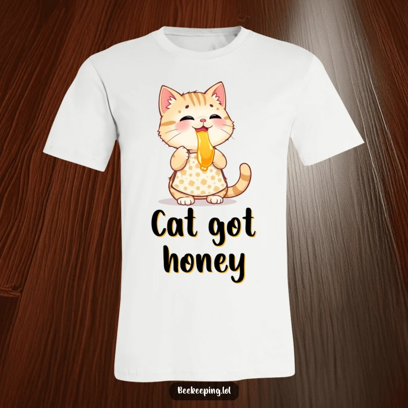 Funny playful cat wearing a patterned apron, tasting honey, a humorous graphic tee for cat enthusiasts.